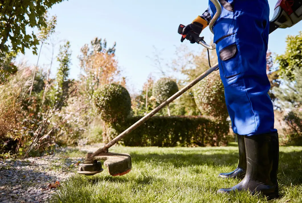 Gardener with weedwacker cutting the grass in the garden Gardener with weedwacker cutting the grass in the garden